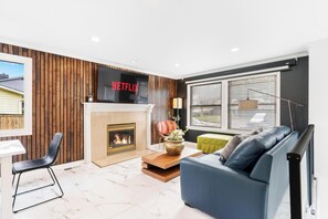 Ein modernes Wohnzimmer mit Kamin, einem blauen Sofa und einem Netflix-Schild an der Wand.