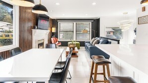 A modern kitchen with a central island, dining area, and seating.