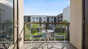 A balcony with a table and chairs, a view of a building, and a metal fence. - Pure Suites 2 Bed Downtown Phoenix Pool Gym (Phoenix)