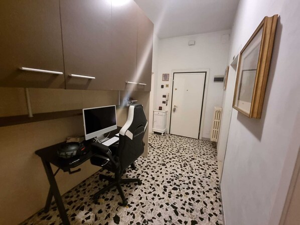 A room with a desk, computer, chair, and a door.