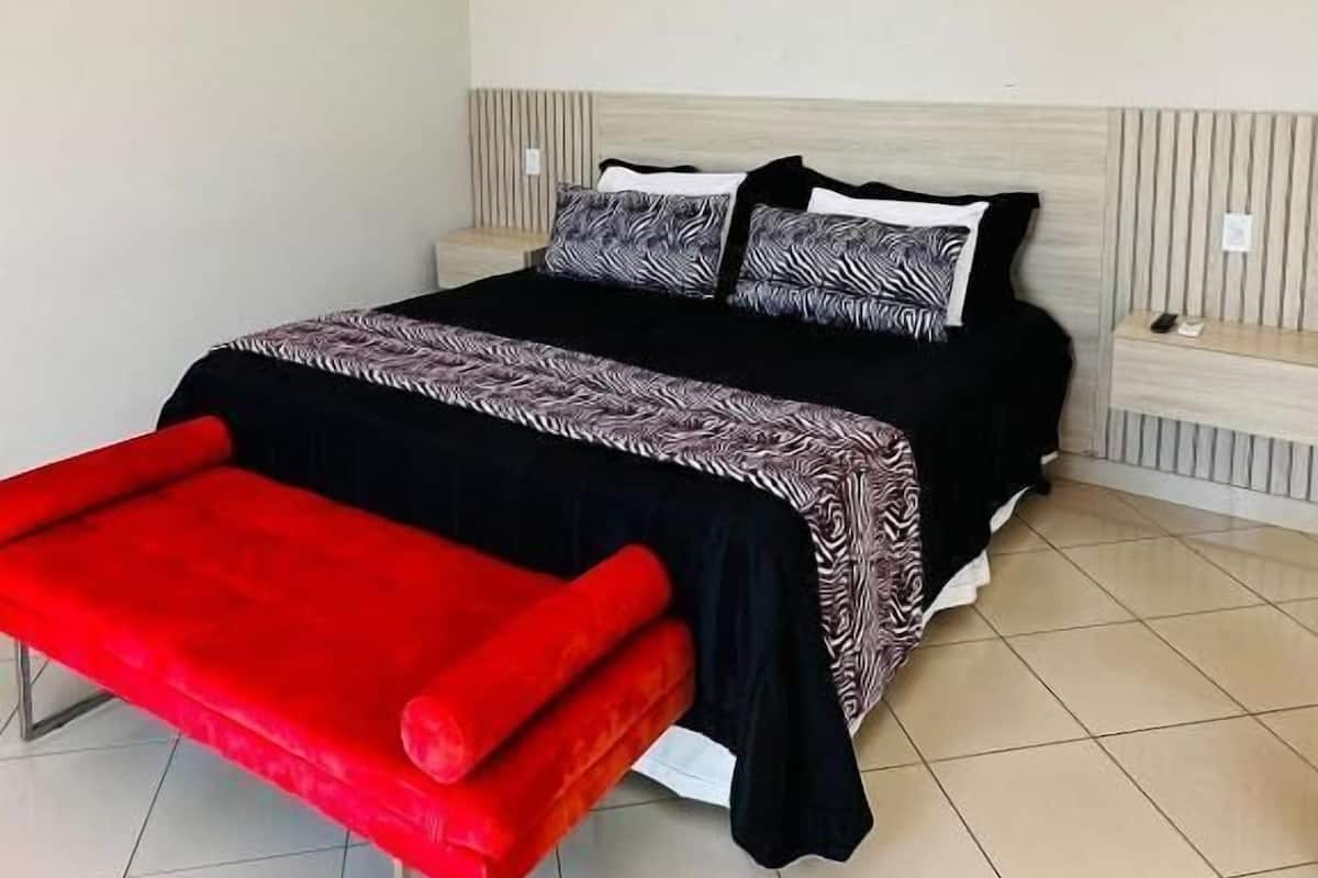 Een slaapkamer met een bed, een rode bank en een wit plafond.