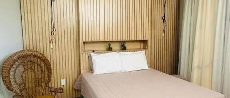Ein Schlafzimmer mit einem Bett, einem Korbstuhl, Holzvertäfelung an den Wänden und einem Deckenventilator.