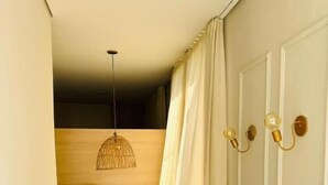 Ett rum med trägolv, ett runt bord med en stol, en hängande lampa och en dörr med vägglampor.