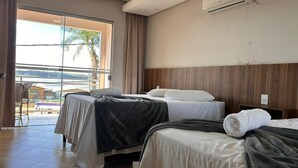 Ett hotellrum med två sängar, en balkong med utsikt över havet och en luftkonditioneringsanläggning på väggen.