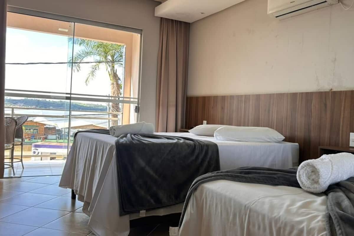 Een hotelkamer met twee bedden, een balkon met uitzicht op zee en een airconditioning aan de muur.