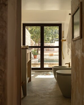 Une salle de bain avec une grande fenêtre, une baignoire et des toilettes.
