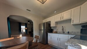 Una cocina moderna con gabinetes blancos, un refrigerador de acero inoxidable y una encimera de granito.