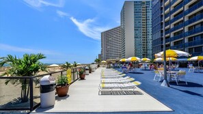 A rooftop terrace with sun loungers, umbrellas, and potted plants. - 20th-Floor Oceanfront Condo with Balcony, Pools, Beach Access & Resort Amenities (Ocean City)