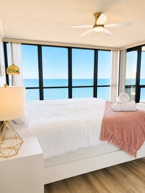 A bedroom with a bed, a ceiling fan, a lamp, and a view of the sea. - 20th-Floor Oceanfront Condo with Balcony, Pools, Beach Access & Resort Amenities (Ocean City)
