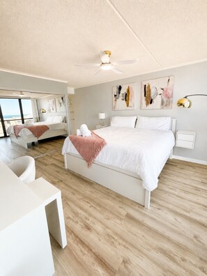A modern hotel room with a large bed, a desk, and a ceiling fan. - 20th-Floor Oceanfront Condo with Balcony, Pools, Beach Access & Resort Amenities (Ocean City)
