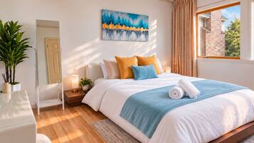 A modern bedroom with a large bed, a bedside table with a lamp, a mirror, and a painting on the wall.