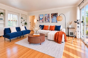 A modern living room with a blue sofa, a white sofa, and a round coffee table. There are paintings on the wall and a telescope on a stand.