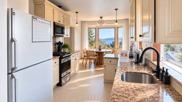 Una cocina moderna con refrigerador, estufa y microondas. Hay un comedor con mesa y sillas. La cocina tiene un ventanal con vistas a la ciudad.