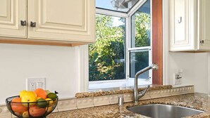 A kitchen with a granite countertop, stainless steel sink, and a fruit bowl.