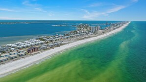 An aerial view of a coastal town with a long beachfront, a pier extending into the water, and a mix of residential and commercial buildings. - Boardwalk A18 | Beach Access & Pool | New Listing! (Pensacola Beach)