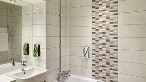 Une salle de bain moderne avec deux lavabos, une douche et un mur recouvert de carreaux formant un motif en mosaïque.