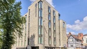Un bâtiment moderne doté d’une façade en pierre et de nombreuses fenêtres.