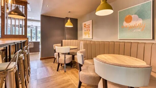 Un intérieur moderne avec un bar en bois, un espace salon et des luminaires suspendus.