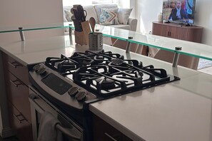 A modern kitchen with a gas stove, oven, and a glass-top island. - 2 Bedroom- Midtown Manhattan apartment with Empire State Building View (New York)