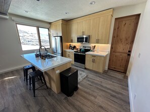 Una cocina moderna con armarios de madera, electrodomésticos de acero inoxidable y una isla grande con taburetes.
