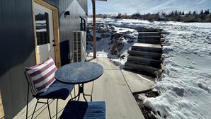 Eine überdachte Terrasse mit Tisch, Stühlen, einer Tür und einer Klimaanlage.