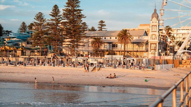 A beachside view with a boardwalk, beach umbrellas, and a Ferris wheel.