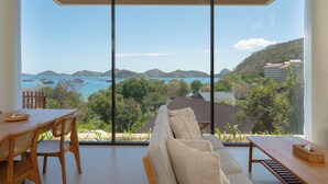 Ein modernes Zimmer mit großem Fenster und Blick auf das Meer und die Berge.