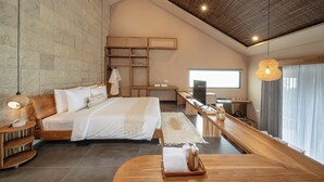 Ein modernes Schlafzimmer mit einem großen Bett, einem Holztisch, einem Fernseher und einer Steinwand.