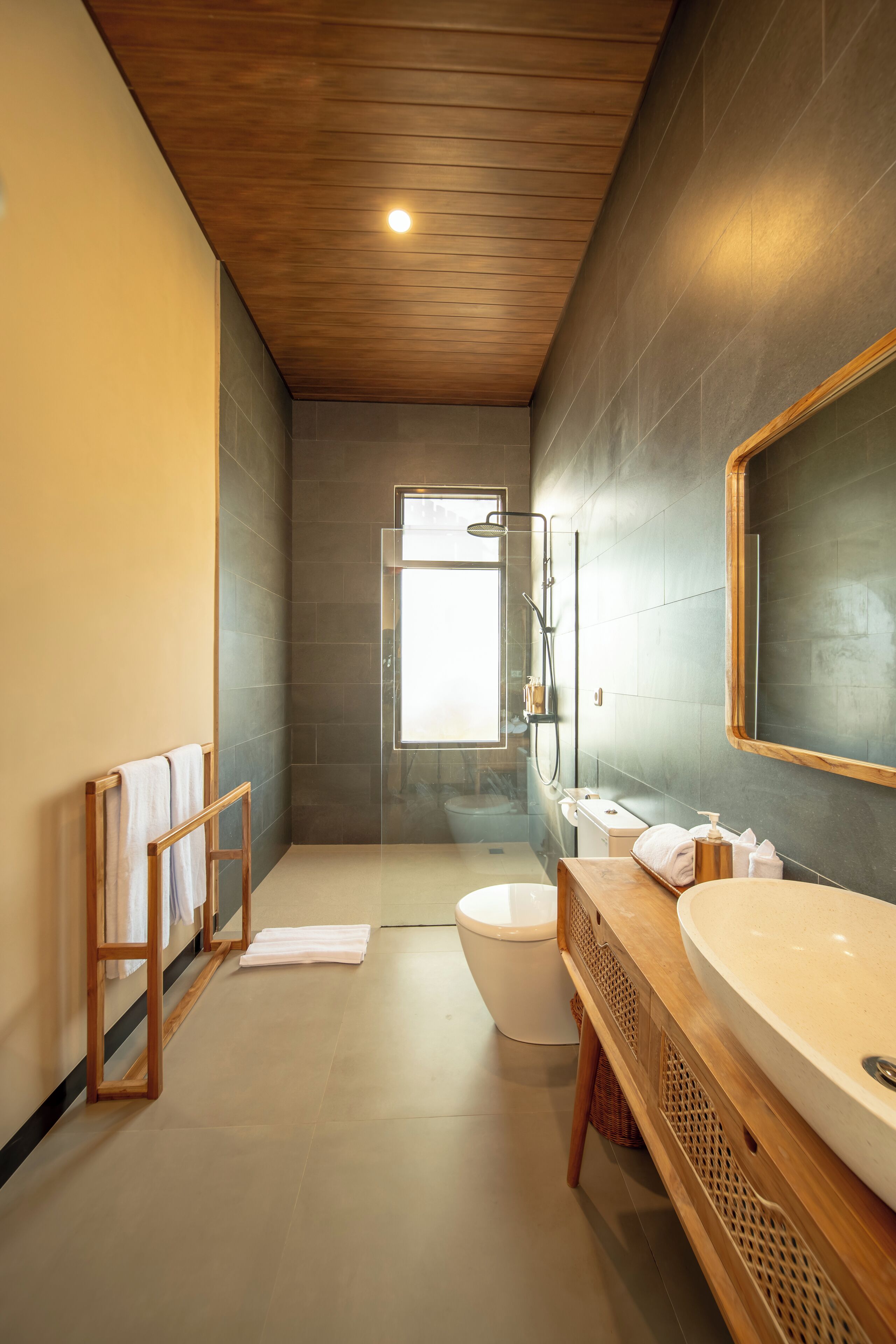 A modern bathroom with a wooden ceiling, a large mirror, a bathtub, and a shower area.