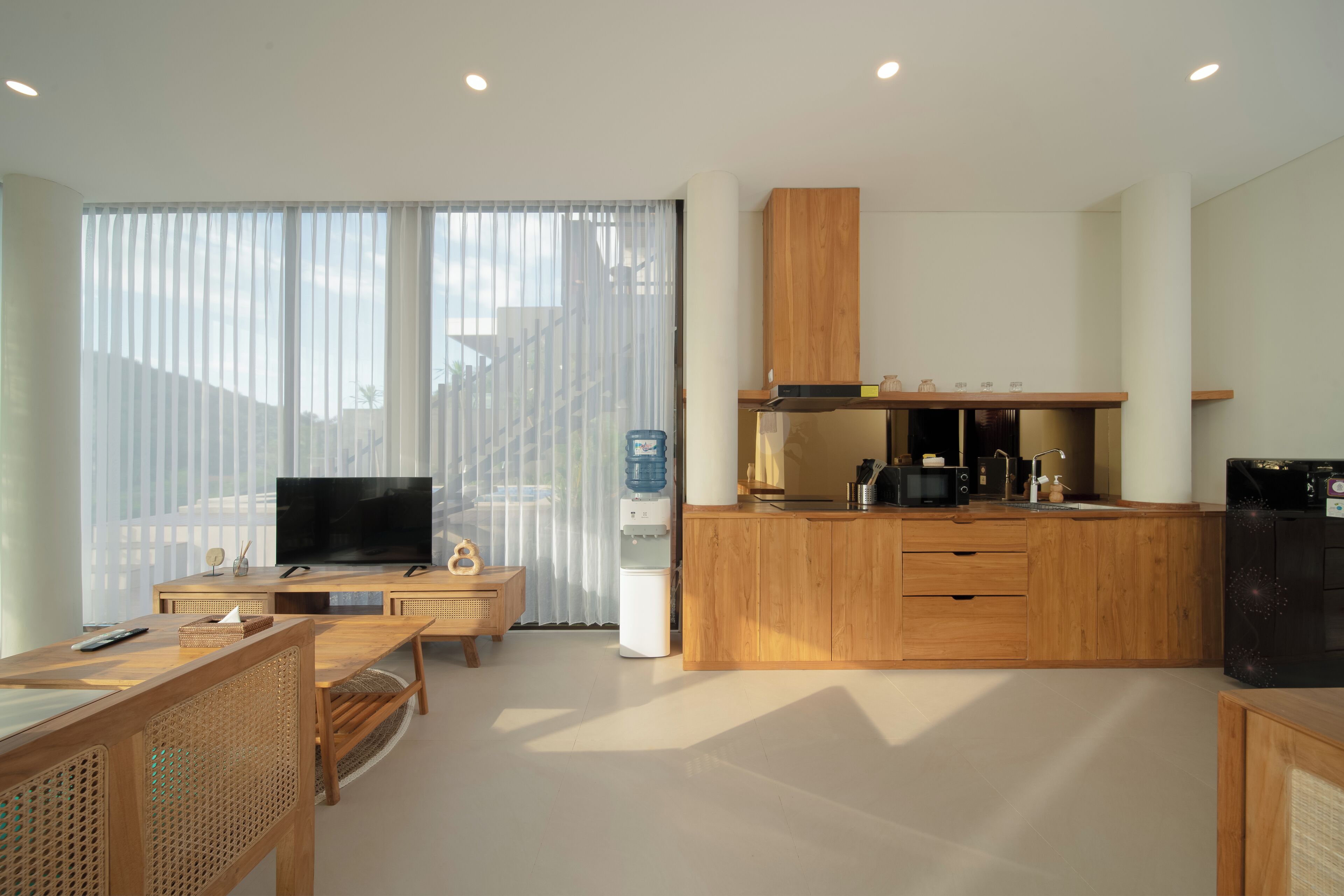 Una cocina moderna con armarios de madera, microondas integrado y dispensador de agua.