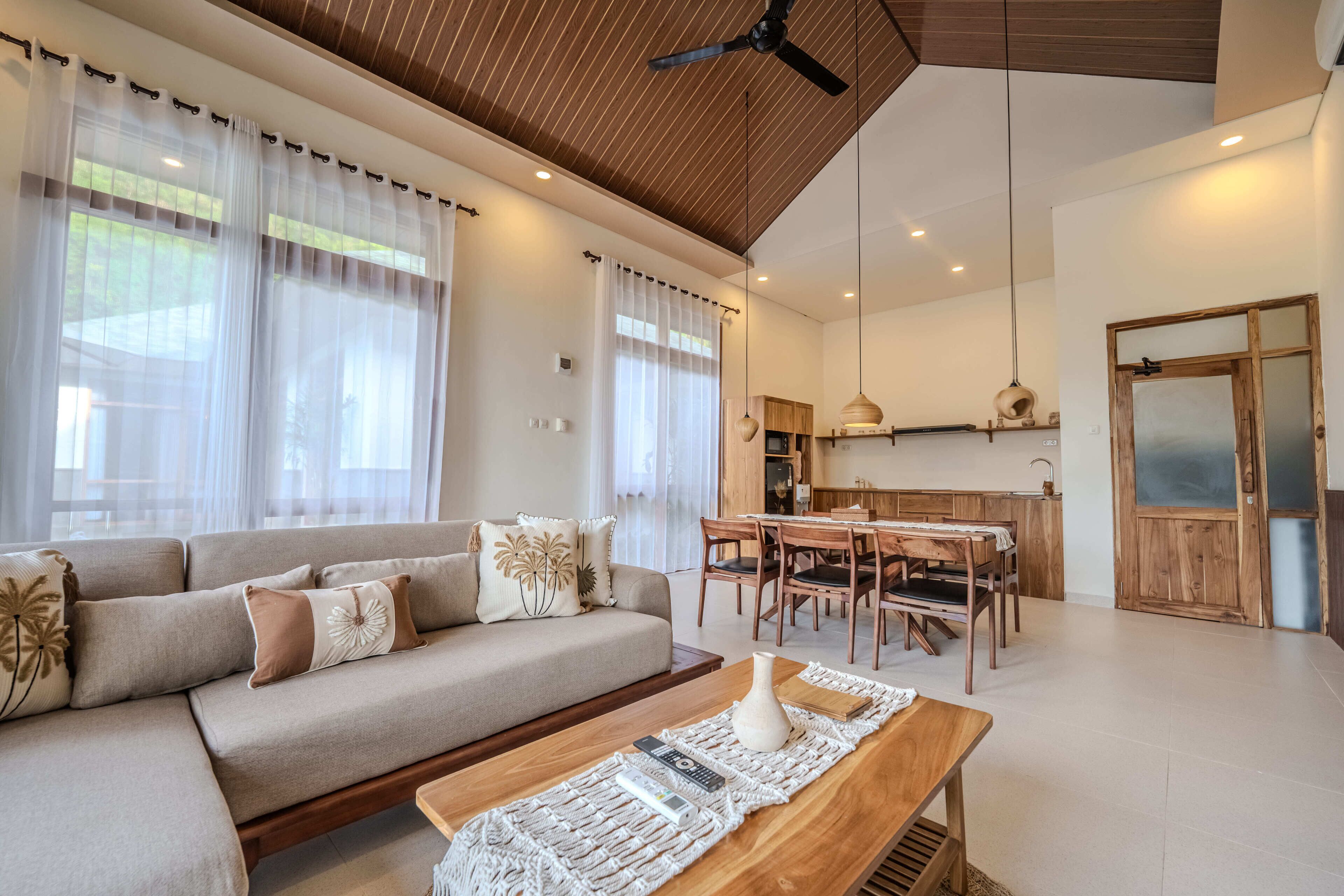A modern living room with a sofa, dining table, and kitchen area.