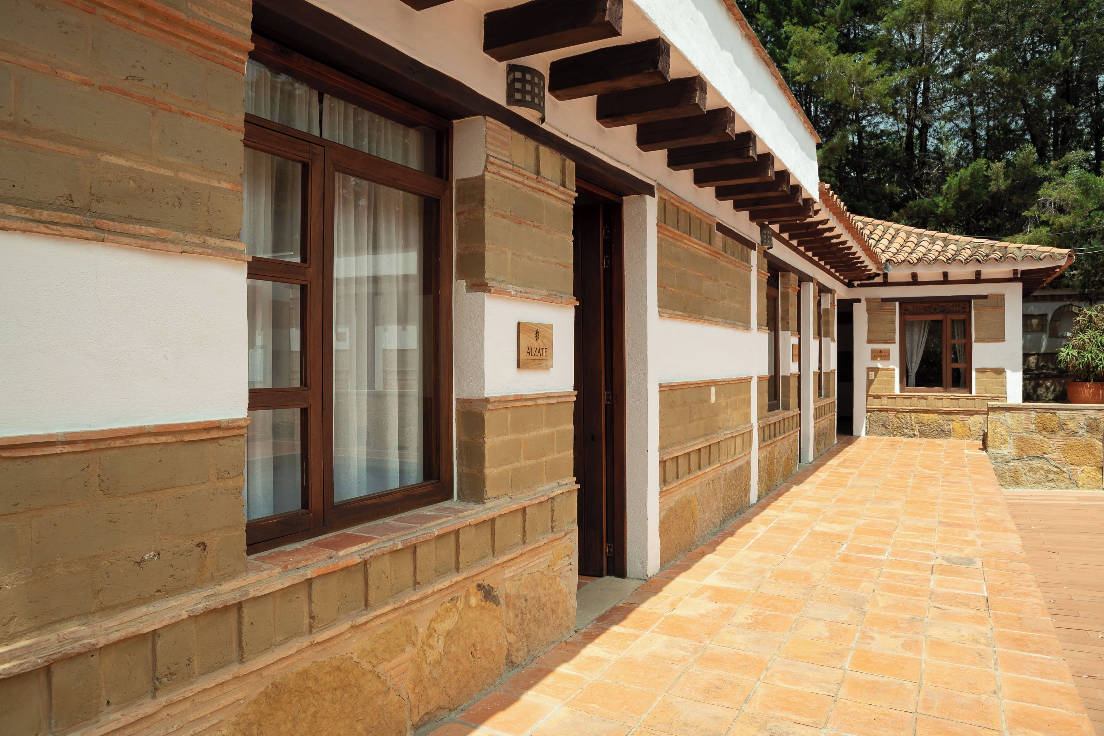 A building with a tiled walkway, wooden beams, and a brick facade.