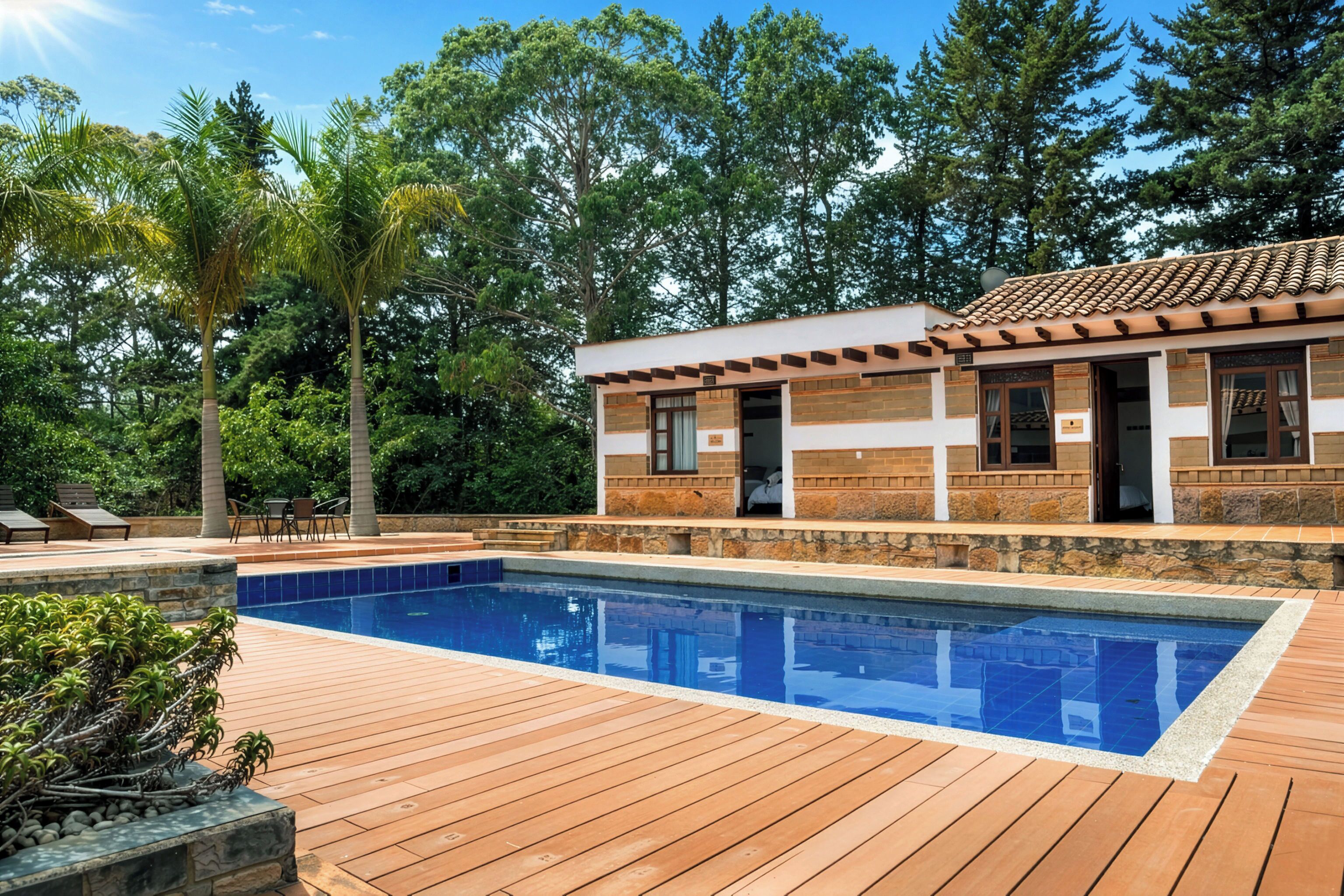Zona junto a la piscina con una terraza de madera, una pileta y un edificio con tejado de tejas.