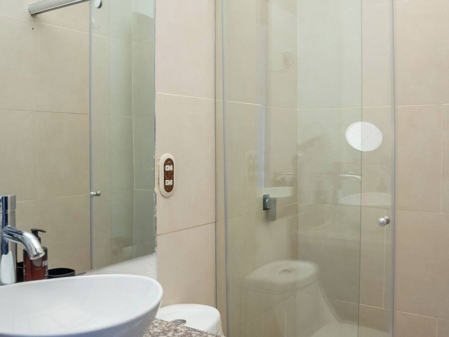 A bathroom with a glass-enclosed shower, a white sink, and a toilet.