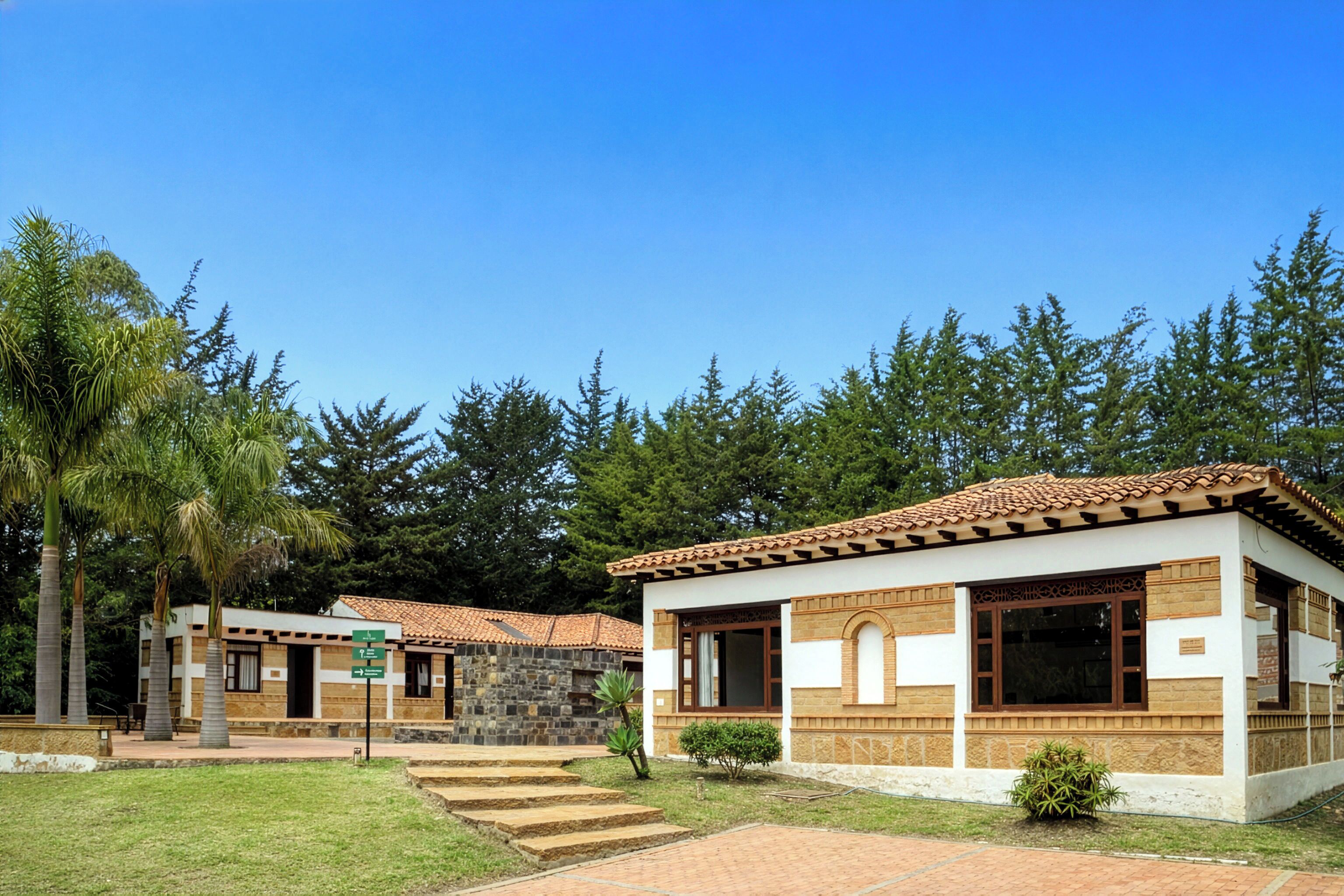 A building with a tiled roof, stone walls, and a paved entrance area with steps.