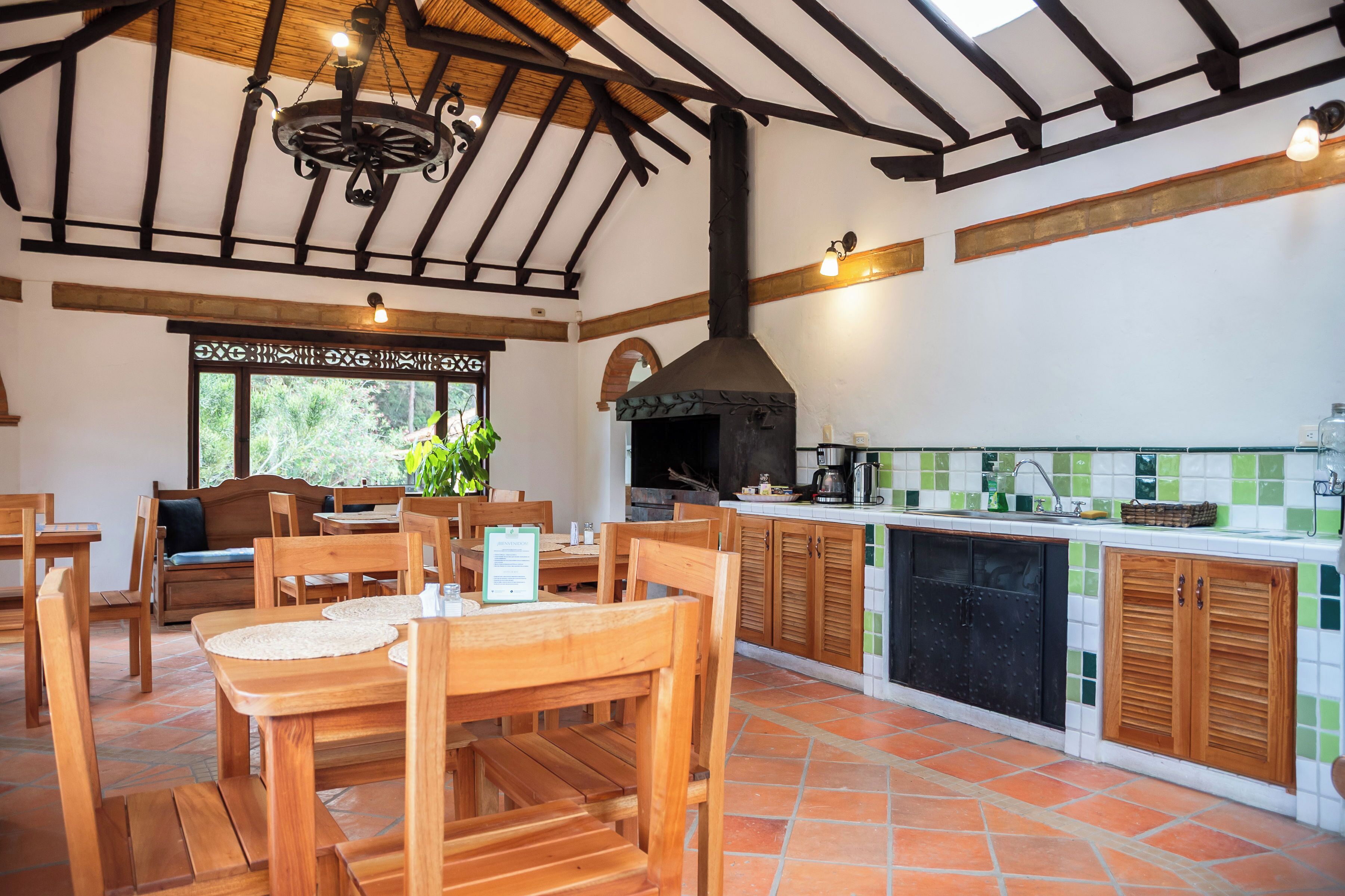 A rustic kitchen with wooden furniture, a chimney, and a tiled backsplash.