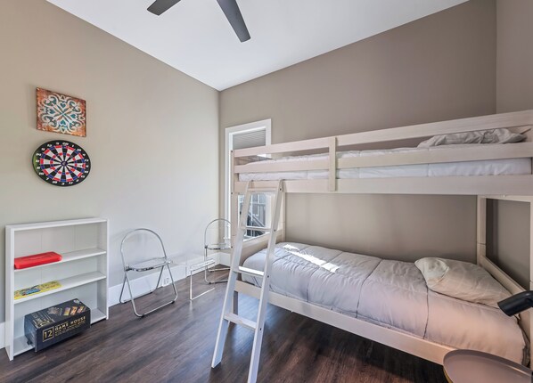 A bunk bed room with a desk, chair, and a dartboard on the wall.