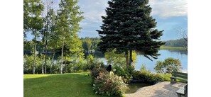Un jardín tranquilo junto al lago, con un banco y un sendero pavimentado.
