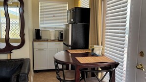 A compact kitchen with a dining area, including a table with chairs, a refrigerator, and a microwave.