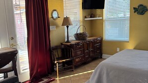 A bedroom with a bed, a desk, a chair, a dresser, and a ceiling fan.