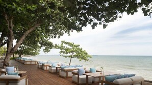 A wooden deck with outdoor seating, overlooking a body of water. - Mercure Rayong Lomtalay Villas and Resort (Klaeng)
