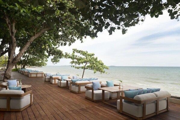A wooden deck with outdoor seating, overlooking a body of water. - Mercure Rayong Lomtalay Villas and Resort (Klaeng)