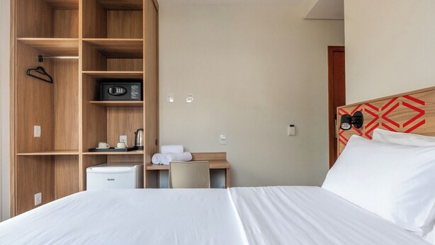 Una camera d'albergo con un letto, una scrivania, angolo cottura e un armadio.