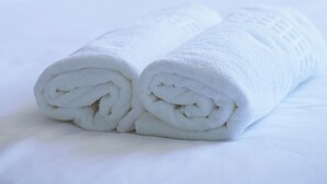 Un letto rifatto con due asciugamani bianchi arrotolati sopra.