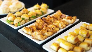 Un buffet con diverse pietanze, tra cui pasticcini, panini e panini assortiti.