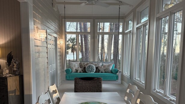 A dining area with a white table, white chairs, a teal sofa, and a ceiling fan. - Pink Paradise aka The Purple House (Daufuskie Island)