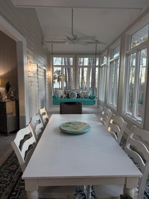 A dining area with a white table, white chairs, a teal sofa, and a ceiling fan. - Pink Paradise aka The Purple House (Daufuskie Island)