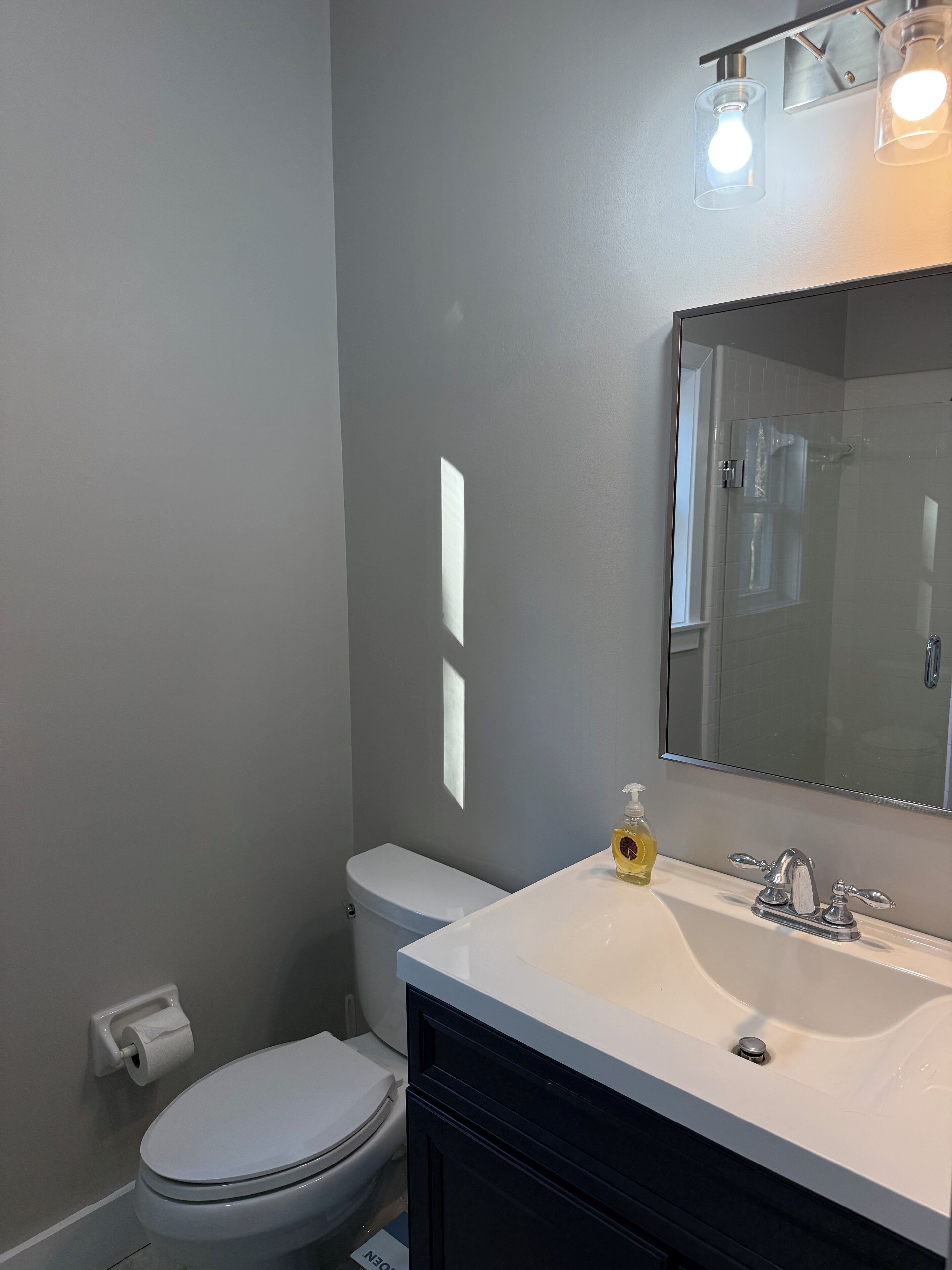 Un baño con inodoro, lavamanos con espejo y zona de ducha.