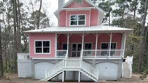 A two-story pink house with a covered porch and a garage. - Pink Paradise aka The Purple House (Daufuskie Island)
