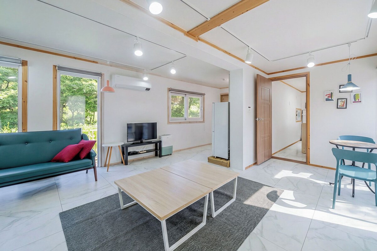 Un salon moderne avec un canapé, un téléviseur et un coin repas comprenant des chaises.